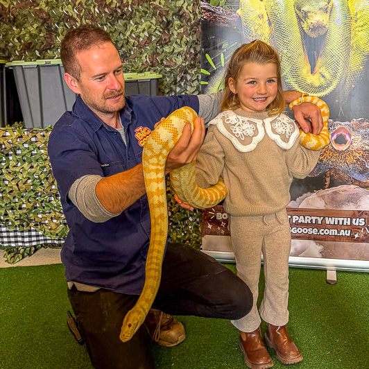 Reptile Encounter at a Big Goose birthday party, the birthday girl holding a huge python with a big smile on her face.